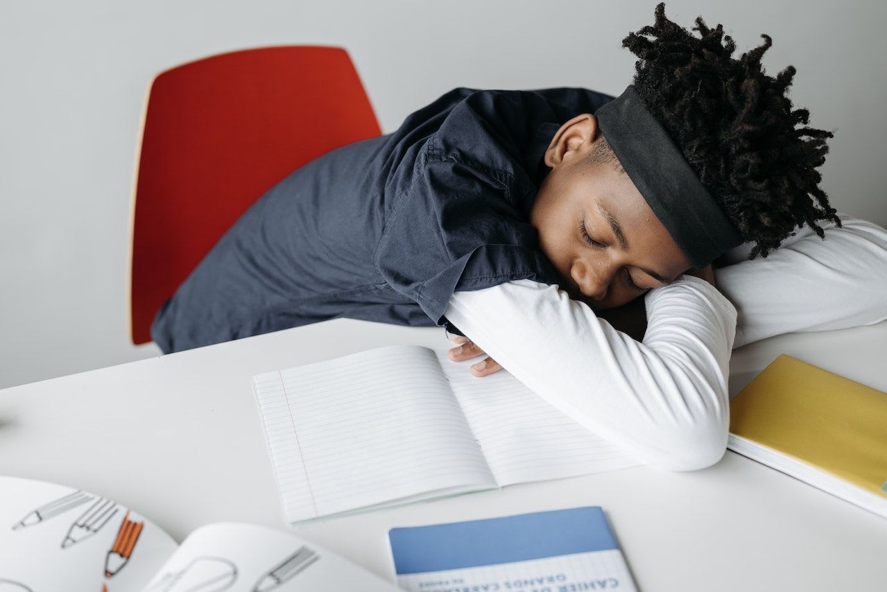 Boy sleeping on desk surrounded by books