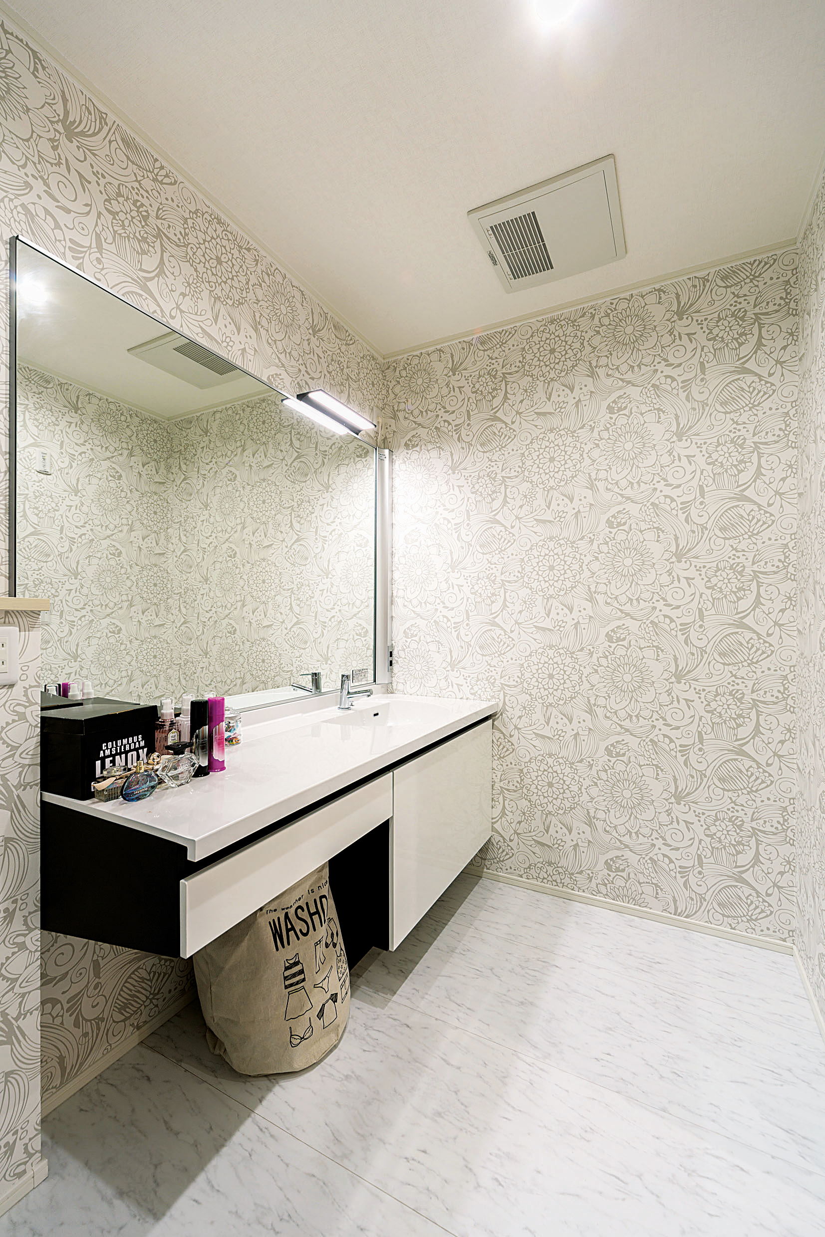 大きな鏡と天板が使いやすい洗面室。大胆な花柄は奥様のセレクト。