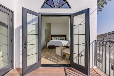 Primary bedroom and French doors opening to a private balcony with seating.