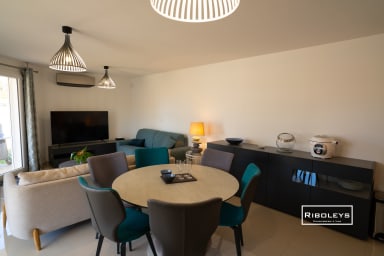 Grande pièce de vie climatisée avec table à manger et cuisine ouverte.