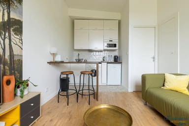 Petit salon avec canapé et cuisine ouverte; ventilateur au plafond, espace...