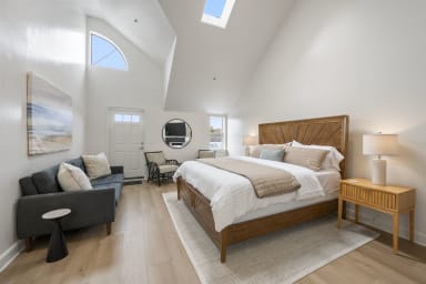 Inviting king bedroom featuring a sofa bed, TV, and cozy fireplace