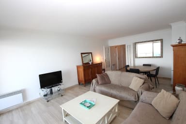 Salon avec table à diner, canapé tv, le tout ouvert sur une terrasse équipée