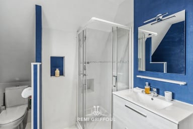 Salle d'eau moderne équipée d’une douche et lavabo au design épuré.