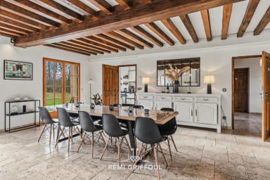 Salle à manger lumineuse avec poutres en bois et vue jardin pour vos repas.