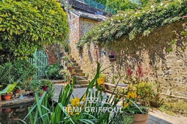 Terrasse entourée de verdure et murs anciens, invitant à la détente en plein ai
