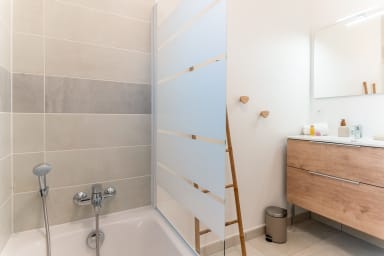 Salle de bain avec baignoire, paroi vitrée et meuble vasque