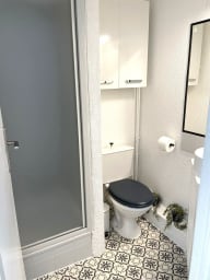 Salle d'eau avec douche, sèche-cheveux, et toilettes
