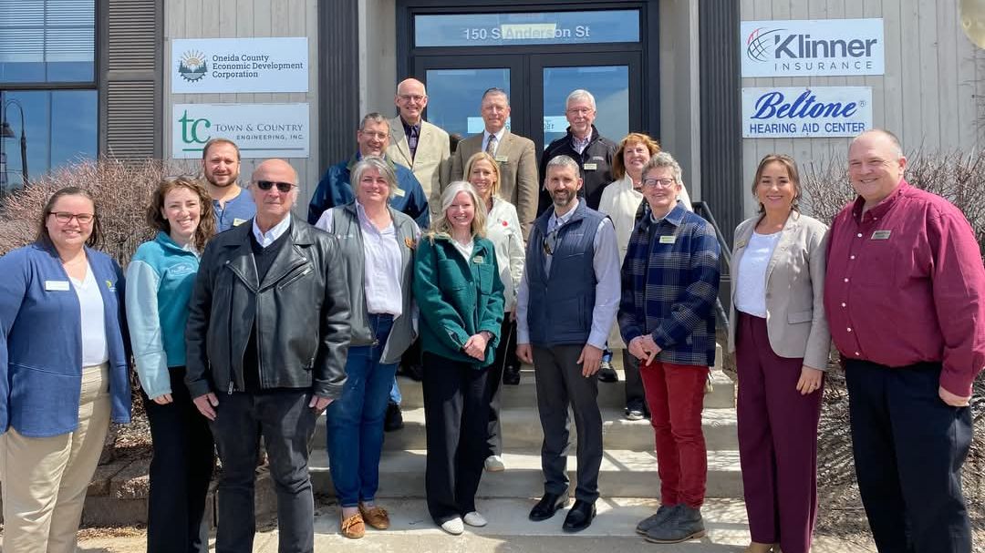 Group of people standing in front of the Oneida County Economic Development Corporation office building for a ribbon cutting ceremony.