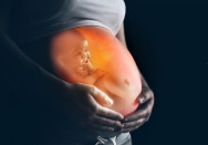 Eine schwangere Frau hält ihren nackten Bauch, auf dem Bauch ist ein Bild eines ungeborenen Babys abgebildet.