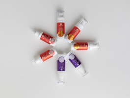 Mehrere Retinol-Seren in roten und violetten Spendern liegen kreisförmig auf weißem Hintergrund.