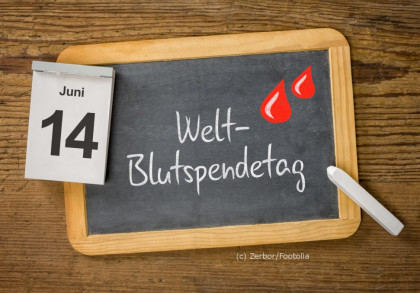 Das Bild zeigt ein Holzset mit einer kleinen Tafel und einem Kalenderblatt. Auf der Tafel steht mit Kreide "Welt-Blutspendetag" und es sind zwei rote Blutstropfen gezeichnet. Das Kalenderblatt zeigt das Datum "14. Juni".