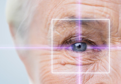 Nahaufnahme des rechten Auges und Kopfes einer alten Frau. Das Auge, genauer die Pupille ist von einer Art Fadenkreuz umgeben.