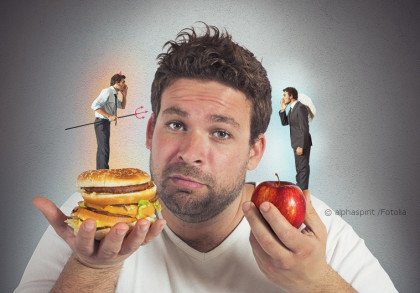 Ein Mann mit einem unschlüssigen Gesichtsausdruck hält in der einen Hand einen Hamburger und in der anderen Hand einen Apfel. Auf seinen Schultern sitzen kleine Figuren, die wie ein Teufelchen und ein Engel aussehen, die ihm ins Ohr flüstern.