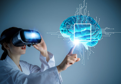 Eine Frau in einem weißen Laborkittel trägt ein Virtual-Reality-Headset und hebt die rechte Hand, um auf ein holografisches Bild eines Gehirns zu zeigen.