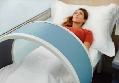 Eine Frau liegt auf einem Krankenhausbett und wird mit einem medizinischen Gerät untersucht.