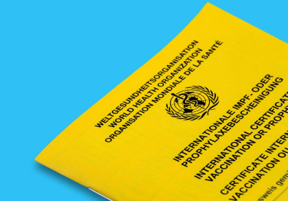 Gelber internationaler Impfpass der Weltgesundheitsorganisation (WHO) auf blauem Hintergrund. Der Impfpass trägt das Logo der WHO und die Aufschrift "Internationale Impf- oder Prophylaxebescheinigung" in mehreren Sprachen.