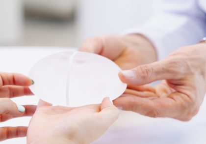 Ärztin zeigt Patientin ein Brustimplantat bei Beratung zur gewebeschonenden Brustvergrößerung in einer plastisch-chirurgischen Praxis.