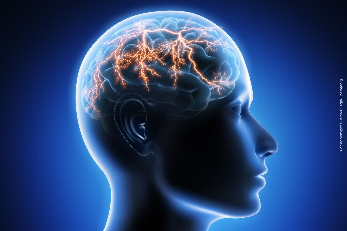 Eine seitliche Ansicht von einem menschlichen Kopf, der in blauen Tönen dargestellt ist. Das Gehirn ist sichtbar und zeigt leuchtende orangefarbene elektrische Aktivität innerhalb des Gehirns. Der Hintergrund ist dunkelblau.
