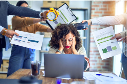 Eine Frau sitzt erschöpft und gestresst vor einem Laptop, während mehrere Hände um sie herum verschiedene Aufgaben und Gegenstände halten, darunter ein Wecker, Papiere und ein Smartphone. Der Schreibtisch ist mit Dokumenten und einem Getränk belegt.