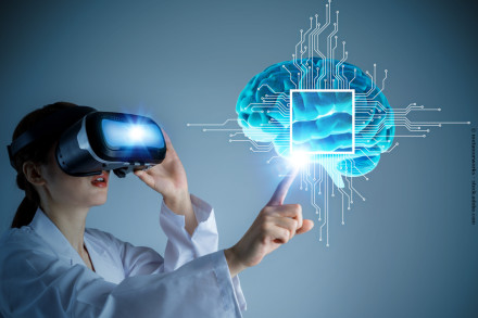 Eine Frau in einem weißen Laborkittel trägt ein Virtual-Reality-Headset und hebt die rechte Hand, um auf ein holografisches Bild eines Gehirns zu zeigen.