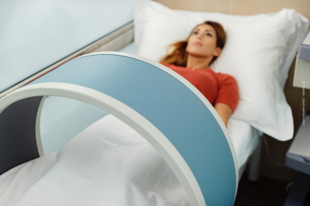 Eine Frau liegt auf einem Krankenhausbett und wird mit einem medizinischen Gerät untersucht.
