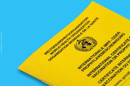 Gelber internationaler Impfpass der Weltgesundheitsorganisation (WHO) auf blauem Hintergrund. Der Impfpass trägt das Logo der WHO und die Aufschrift "Internationale Impf- oder Prophylaxebescheinigung" in mehreren Sprachen.