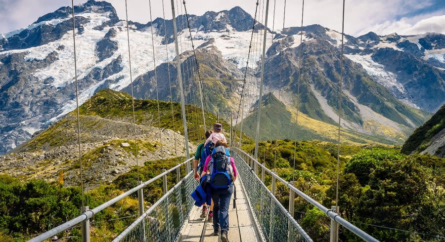 Amazing Nature of Hooker Valley Track in Mount Cook, New Zealand. Young Family walk on Suspension Bridge