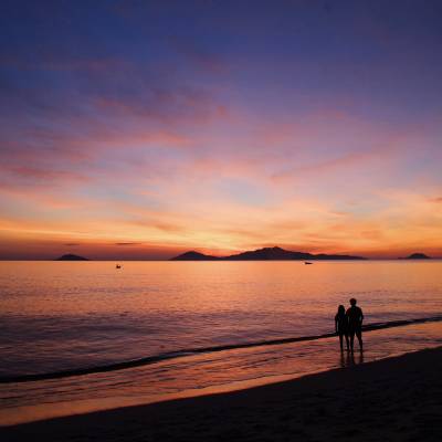 a couple of people on a beach with a sunset in the background