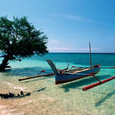 a boat sitting on top of a sandy beach next to the ocean