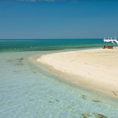 a boat sitting on top of a sandy beach next to the ocean