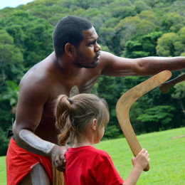 Yirrganydji-Aborigine mit Körperbemalung erklärt kleinem Mädchen die Bedienung eines Boomerangs in Queensland, Australien