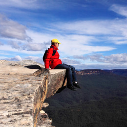 Wanderer sitzt am Rand eines Abgrunds und betrachtet die Blue Mountains, Australien