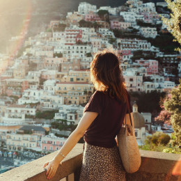 Young woman admiring panoramic view of Positano at sunset, Amalfi coast, Italy