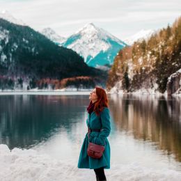 Young redhead girl in coat near lake in Alps, Germany Tours