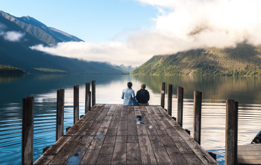 couple in love sitting on the pier at Nelson Lake National Park in the South Island of New Zealand