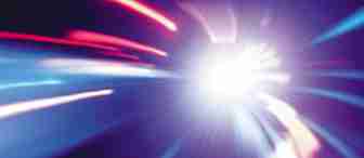 A dynamic, abstract image with streaks of light in blue, red, and purple hues radiating from a bright, central point. The lights create a sense of motion and speed, with blurred lines and a gradient background adding to the energetic effect.