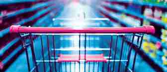 A shopping cart with a red handle is in the aisle of a grocery store. Shelves filled with various products blur into the background, creating a sense of depth and focus on the cart. The lighting is bright, giving the scene a fresh and vibrant atmosphere.