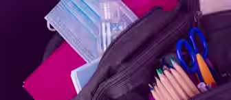 A backpack is open, revealing school supplies including colored pencils, blue-handled scissors, notebooks, and a small bottle of hand sanitizer. Two blue surgical masks are also visible on top of the notebooks. Purple background.