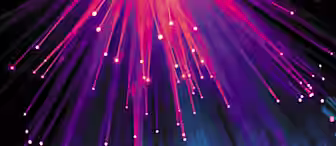A display of colorful fiber optic lights emanating outward, creating streaks and points of vibrant pink, purple, and blue against a dark background. The lower part of the image features a bokeh effect with blue and pink glowing circles.
