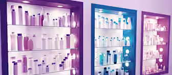 Three illuminated display shelves, each differently colored (purple, blue, and pink), showcasing various bottles, jars, and containers commonly used for cosmetics or personal care products. The items are neatly arranged, creating a visually appealing presentation.