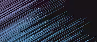 A digital illustration featuring diagonal light streaks in blue and pink shades against a dark, almost black, background. The streaks appear to be moving from the upper left to the lower right, creating a sense of motion and energy.