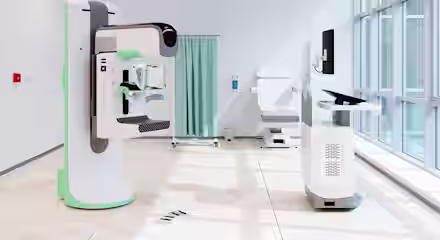 A modern, bright medical room with advanced diagnostic machines, a computer workstation, an examination chair, and a green privacy curtain near large windows letting in natural light.