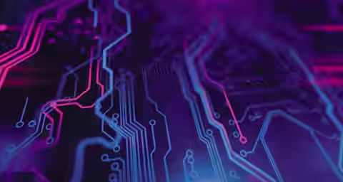 Close-up view of a digital circuit board featuring pink and blue neon lines against a dark purple background. The intricate pathways and glowing colors create a futuristic and high-tech appearance.