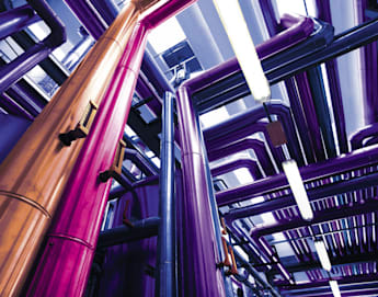 A vibrant and colorful industrial scene with tall metallic pipes in shades of purple, pink, and copper running in various directions under bright lighting. The pipes are part of a complex system, creating a visually striking and futuristic environment.