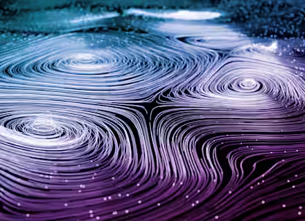 Abstract image illustrating fluid dynamics with swirling, curving lines in shades of blue, white, and purple. The lines form intricate vortex shapes, evoking the appearance of a flowing liquid or energy pattern. Small white dots are scattered throughout.