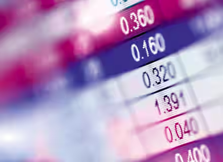 Close-up image of a digital financial display showing various numbers and statistics, possibly stock market or exchange rates, with bright, blurred colors in the background. The text on the screen includes numbers like 0.360, 0.160, and 0.320.
