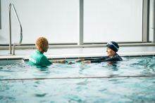 An adult learning to swim with an instructor