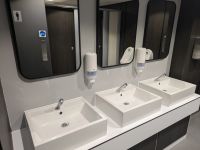 A photo of the male changing room showing the new vanity area. Three new modern basins and black-framed mirrors.
