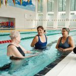 Image shows three women in conversation in a swimming pool